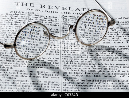 Old fashioned reading glasses on a page from the Bible open at book of The Revelation Stock Photo