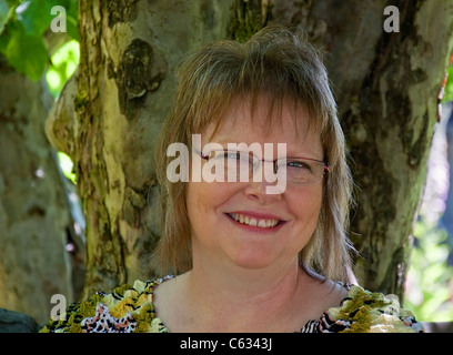This happy, middle aged Caucasian woman in smiling in an up close, head shot outdoors. She's got light brown, short hair . Stock Photo