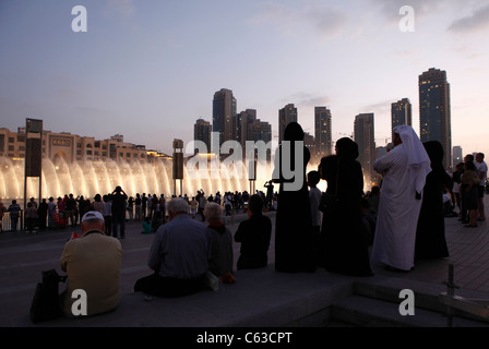 Spectators watching the water and light display of the Dubai Fountain on Burj Khalifa Lake at dusk in Dubai, Stock Photo