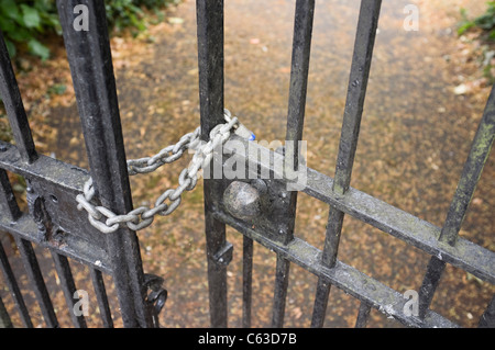 England, UK, Britain. Close-up of padlock on a chain locking wrought iron gates at the entrance to a school Stock Photo