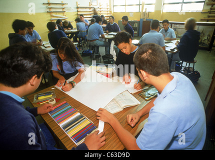 Study group with art materials at desk in elementary school classroom with teacher and students in Caracas, Venezuela Stock Photo