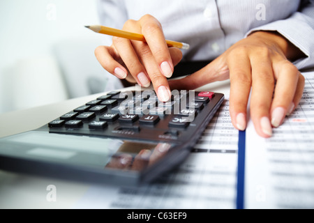 Photo of hands holding pencil and pressing calculator buttons over documents Stock Photo