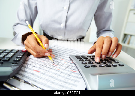 Photo of hands making notes with pencil and pressing calculator buttons Stock Photo