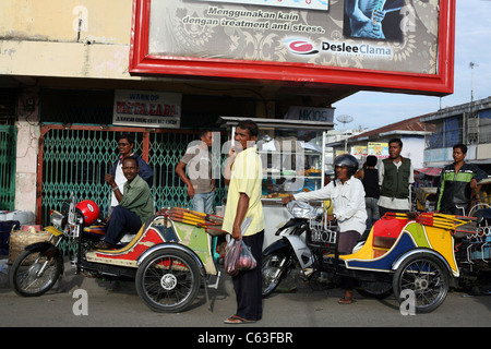 Motor taxi tuk tuk drivers waiting for the afternoon rush in the city center. Stock Photo