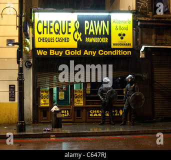 Two police officers guard a pawn shop in Brixton during the 2011 London riots. Stock Photo