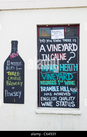 Two wall signs outside a wine shop publicizing success of new local English wine produced from grapes grown in Wiltshire Stock Photo