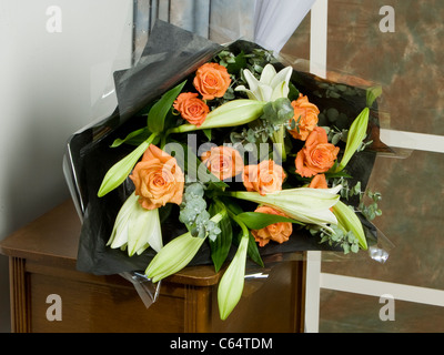 Mixed bouquet of orange roses, white lilies and decoration Stock Photo