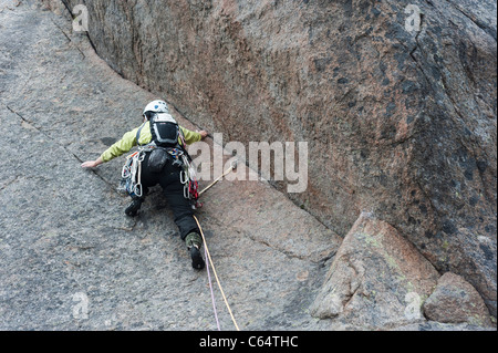 A female rock climber climbing in traditional style in Lofoten Islands, Norway Stock Photo