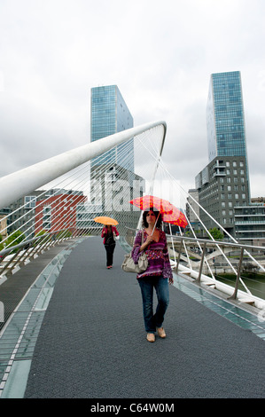Women carrying an umbrella on Santiago Calatrava's Zubizuri Bridge, Bilbao, in the Basque Country of Spain Stock Photo