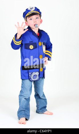 Young boy dressed up as a police officer who is blowing a whistle on white background. Stock Photo