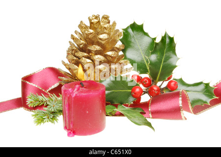 Christmas decoration of golden pine cone burning candle, gold edged ribbon and seasonal foliage Stock Photo
