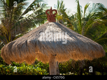 Grass parasol with palm trees in the distance. Stock Photo