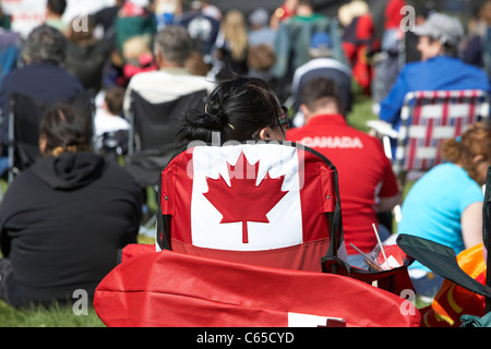 woman sitting in maple leaf chair in the crowd at festival on canada day Saskatoon Saskatchewan Canada Stock Photo