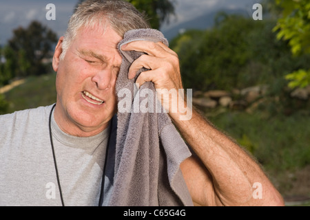 Senior man wiping face with towel after workout Stock Photo