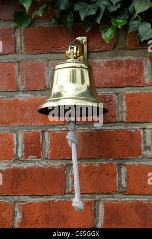 Traditional brass school bell on a brick  wall with ivy Stock Photo