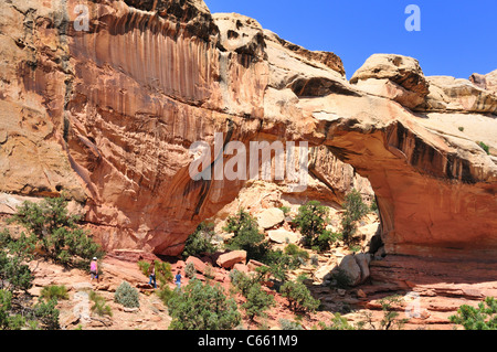 Hikers approach Hickman bridge in Capitol Reef National Park Stock Photo