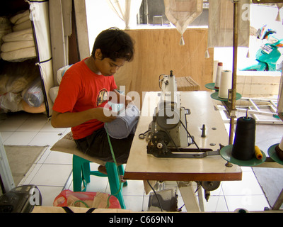 Balinese man working at sewing machine in a roadside tailors shop Stock Photo