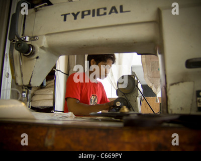 Balinese man working at sewing machine in a roadside tailors shop Stock Photo