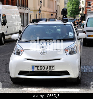 Roof mounted camera on white CCTV surveillance car with driver assistant working & driving along in London West End (obscurred face) England UK Stock Photo