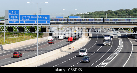 Transport infrastructure railway bridge & carriages of passenger train crossing road traffic at junction 28 M25 motorway Brentwood Essex England UK Stock Photo
