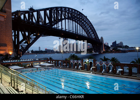 The Olympic swimming pool at North Sydney, showing the Harbour Bridge with the city behind - early evening Stock Photo