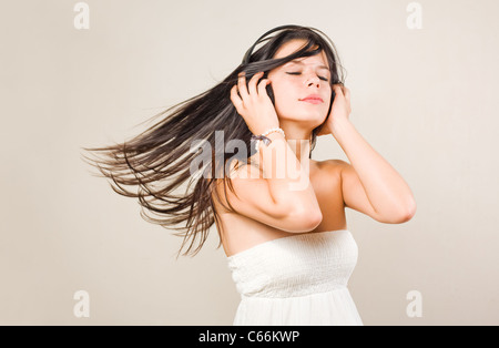 Gorgeous young brunette immersed in music wearing headphones, with eyes closed Stock Photo