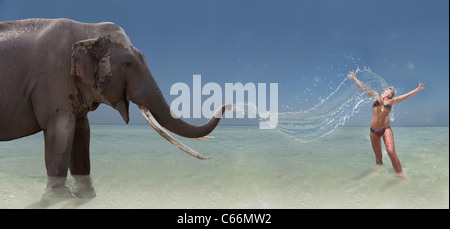 Elephant spraying water on woman Stock Photo