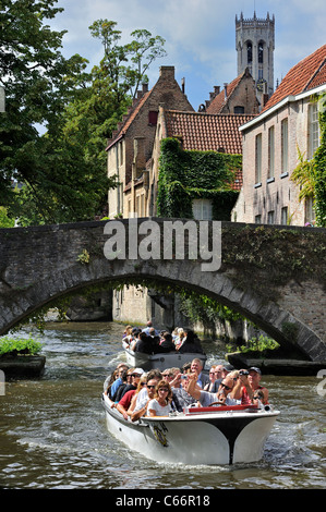 Belfry, old bridge over canal and tourists during sightseeing boat trip along the Groenerei, Bruges, Belgium Stock Photo