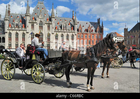 Provincial Court and tourists in horse-drawn carriage for sightseeing tour at the Market square / Grote Markt in Bruges, Belgium Stock Photo