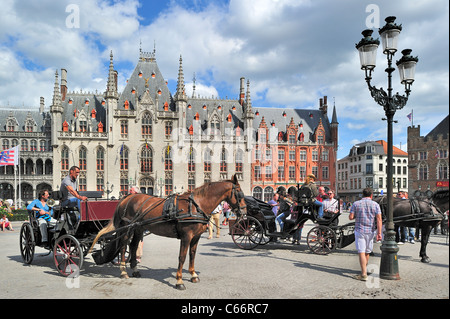 Provincial Court and tourists in horse-drawn carriage for sightseeing tour at the Market square / Grote Markt in Bruges, Belgium Stock Photo
