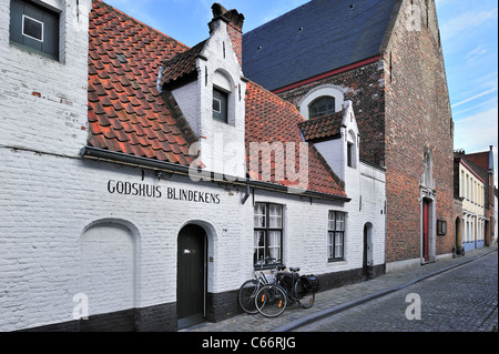 White almshouse Blindekens and chapel along cobbled alley in Bruges, Belgium Stock Photo