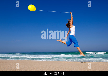Beautiful and athletic Girl jumping with a balloon on the beach