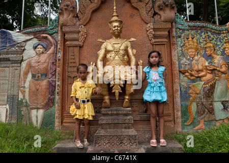 Young children stand next to a statue in Phnom Penh, Cambodia. Stock Photo