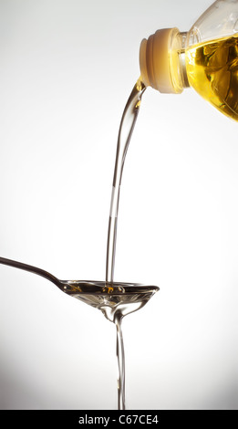 pouring olive oil on spoon, gray background Stock Photo