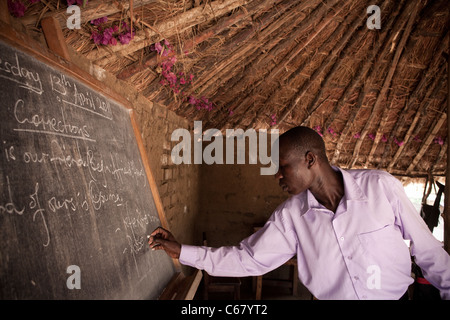A teacher teaches in a grass roof classroom in Amuria, Uganda, East Africa. Stock Photo