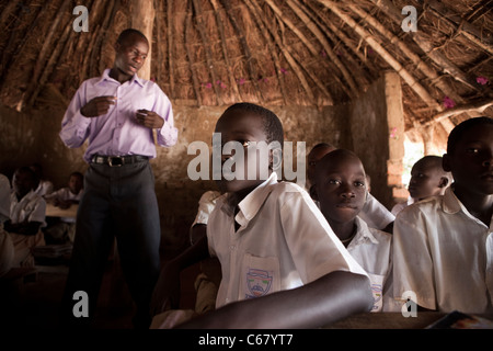 A teacher teaches in a grass roof classroom in Amuria, Uganda, East Africa. Stock Photo