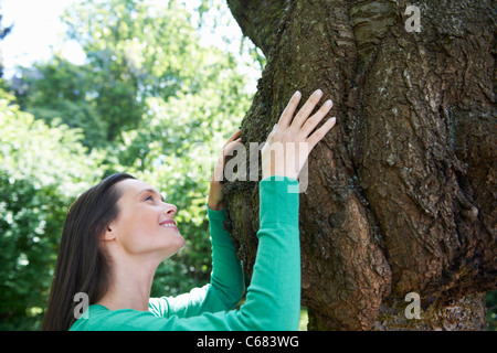 Smiling woman hugging tree Stock Photo
