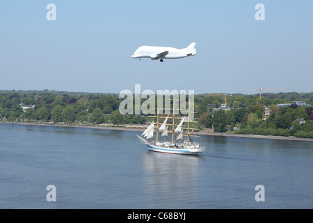 Airbus Beluga freight aircraft flying over sail ship on the Elbe river Stock Photo