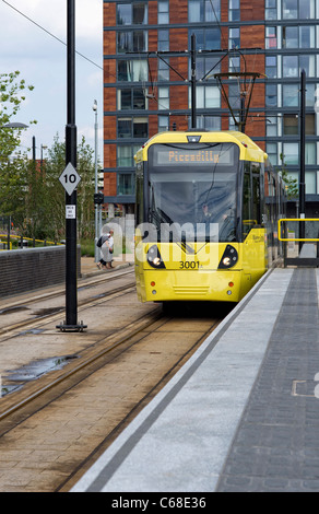 One of the modern yellow trams standing at a platform at MediaCityUK station in Salford Quays (part of the Metrolink system)