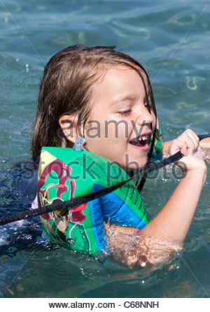 young boy learning how to swim wearing armbands in a swimming pool in ...