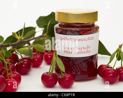 one glass home-made sour cherry jam, sour cherries and sour cherry leaves are besides this Stock Photo