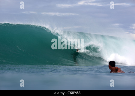 Surfer riding in the tube on a perfect wave on Nias Island in Sumatra, Indonesia. Stock Photo