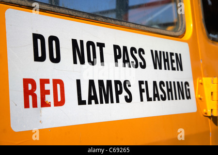 do not pass when red lamps flashing sign on the back of a yellow school bus Saskatoon Saskatchewan Canada Stock Photo