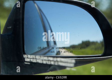 objects in mirror are closer than they appear in car side mirror on highway Canada Stock Photo