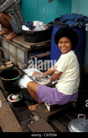 Smiling woman doing the laundry in the Pasar Ikan shantytown, Jakarta, Indonesia Stock Photo