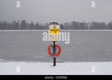 warning ice sign at the round pond in London's Hyde Park after snow with ice on the water Stock Photo