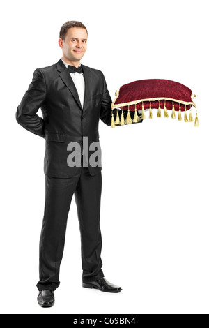 Full length portrait of a man in a black suit holding a pillow Stock Photo