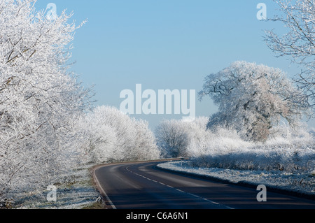 Beautiful view of an empty road winding through the hoar frost covered countryside in rural England during Winter. Stock Photo