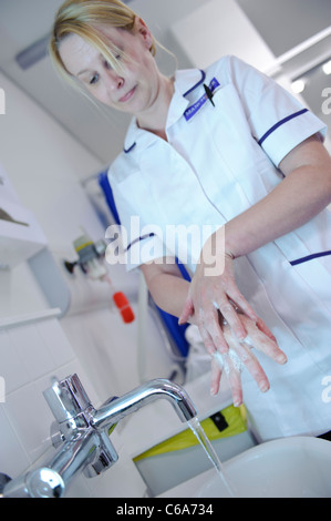 female white nurse washing hands at sink Stock Photo