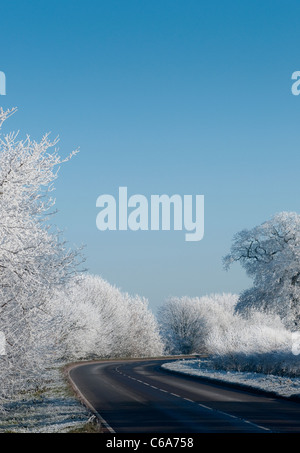 Beautiful view of an empty road winding through the hoar frost covered countryside in rural England during Winter. Stock Photo